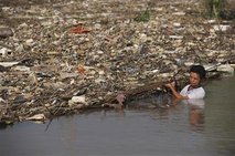 A worker clears floating garbage washed down by recent torrential rain on the Yangtze River in Wuhu